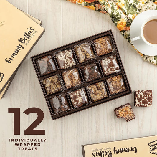 A box of 12 individually wrapped gourmet brownies with assorted toppings, displayed on a wooden table alongside coffee and floral napkins.