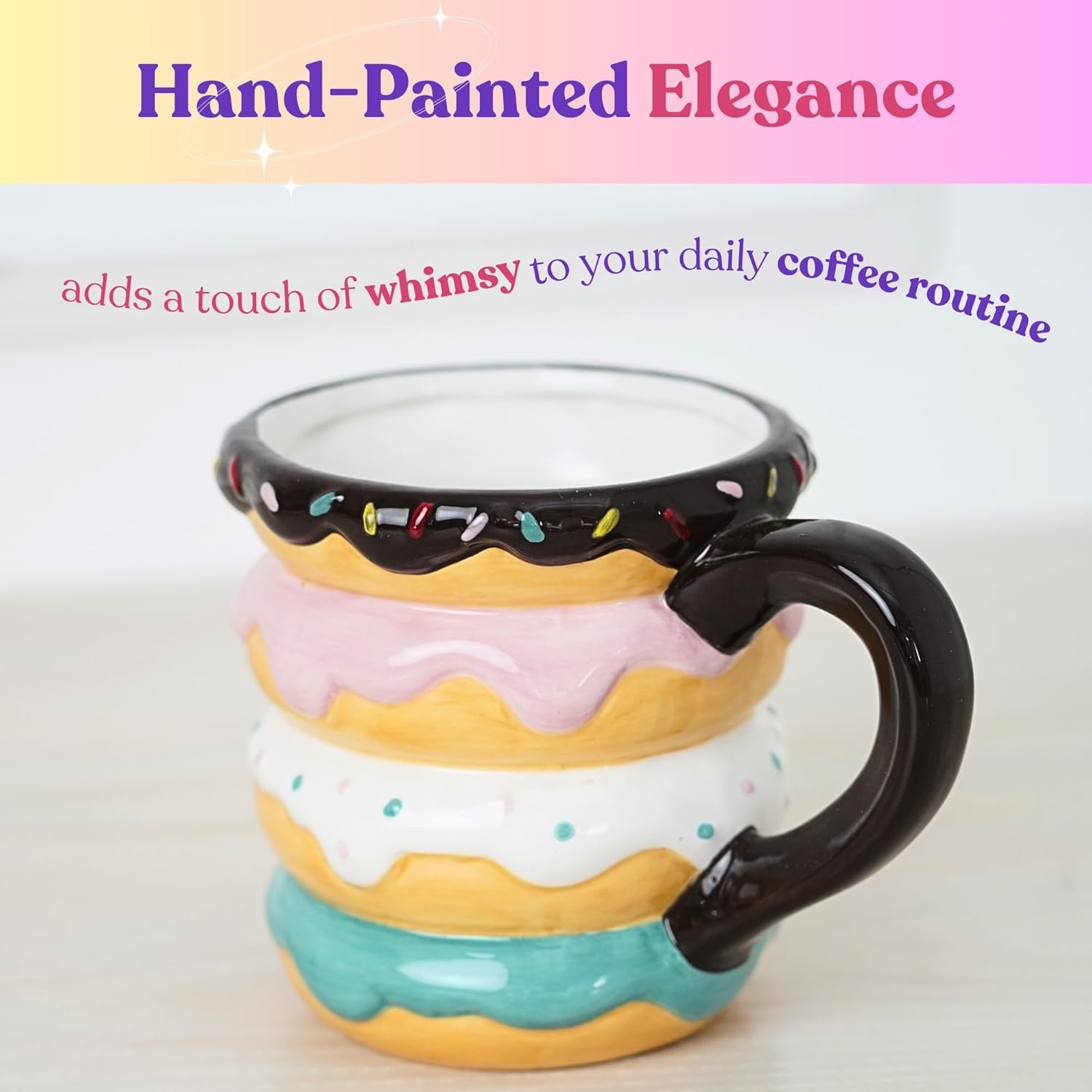 Hand-painted ceramic mug shaped like stacked donuts with pastel frosting and a chocolate glaze rim, featuring a playful design with colorful sprinkles and a black handle.