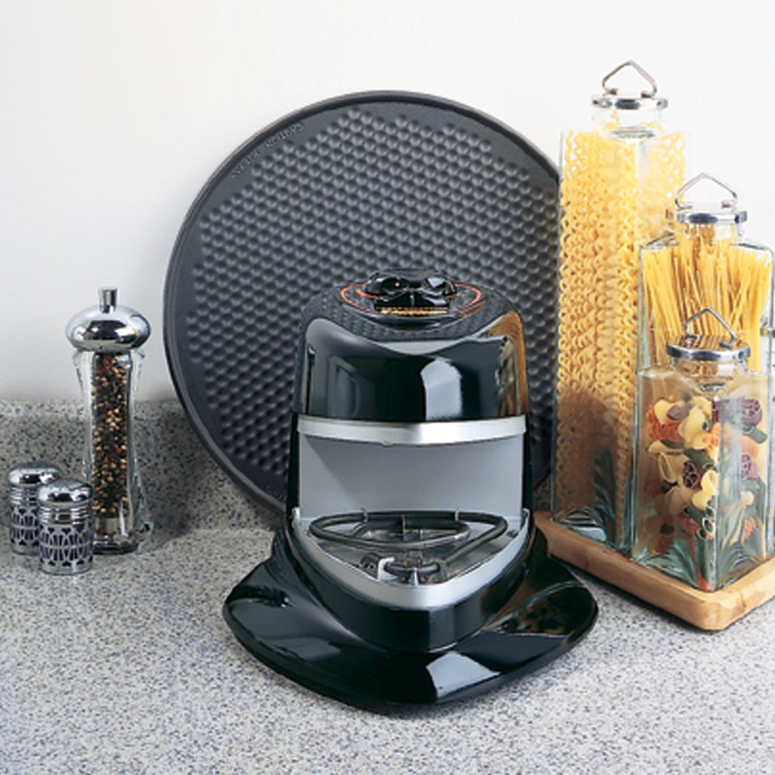 A rotating pizza oven on a kitchen bench with salt and pepper grinders and raw pasta in jars sitting in the background.